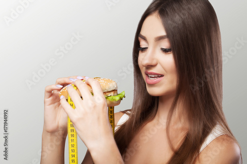 Young girl eating food  burger fast food  American unhealthy dietary calorie Concept of health and beauty On a gray background.