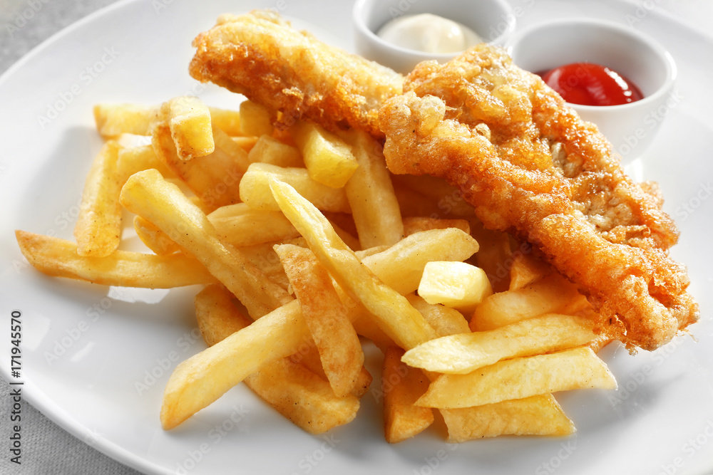 Tasty fried fish, chips and sauces on plate, closeup Tasty fried fish, chips and sauces on plate, closeup