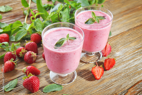 Glasses of fresh strawberry smoothie on wooden table