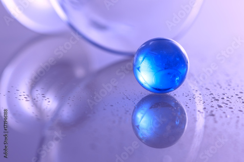 Blue glass ball on a glass table and beautiful abstract background.