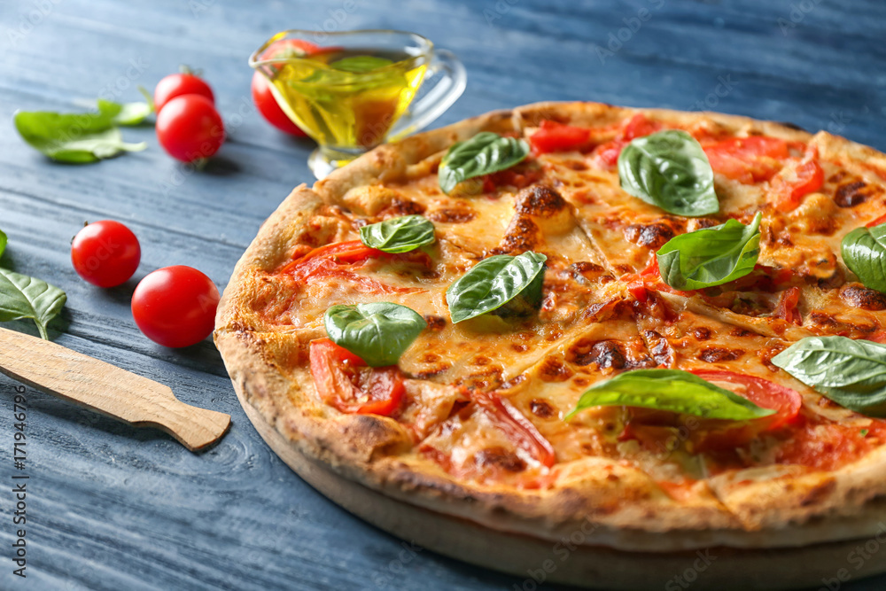 Delicious pizza with tomatoes and fresh basil on kitchen table