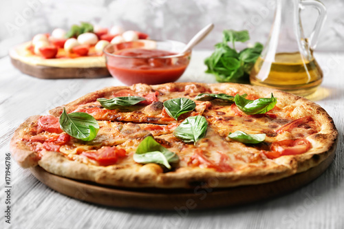 Delicious pizza with tomatoes and fresh basil on kitchen table