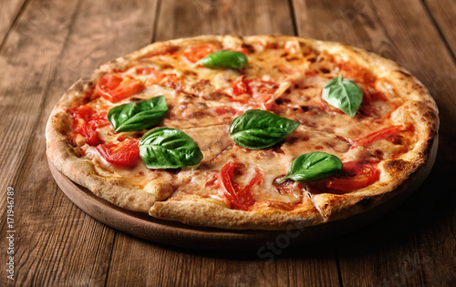 Delicious pizza with tomatoes and fresh basil on wooden background