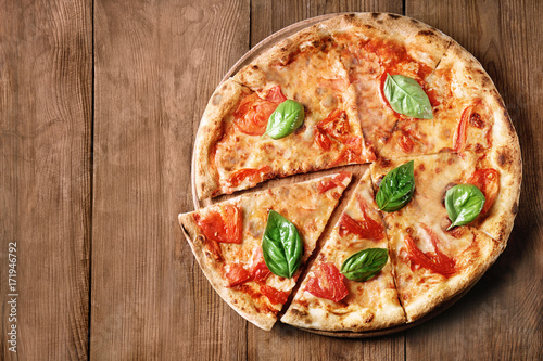 Delicious pizza with tomatoes and fresh basil on wooden background