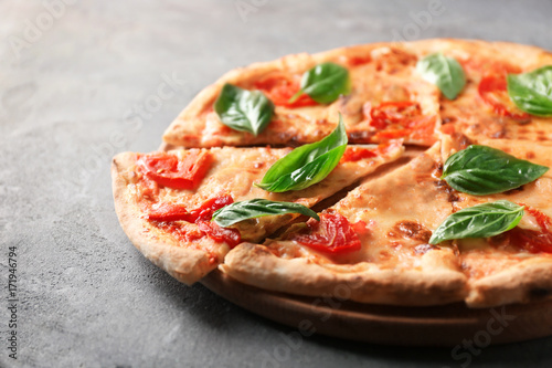 Delicious pizza with tomatoes and fresh basil on grey background