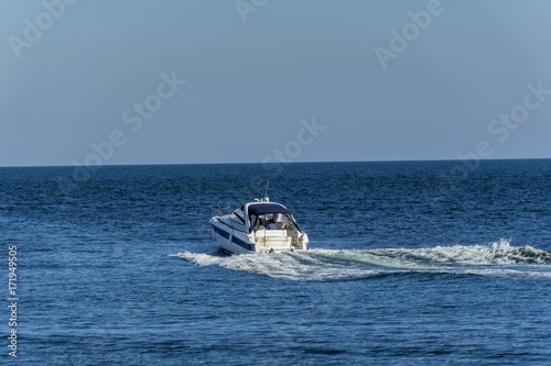  White cabin cruiser over blue water. A luxury private motor yacht under way on Black Sea sea with bow wave.
