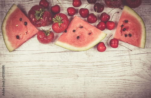 Watermelon, strawberries and cherries on wooden background.