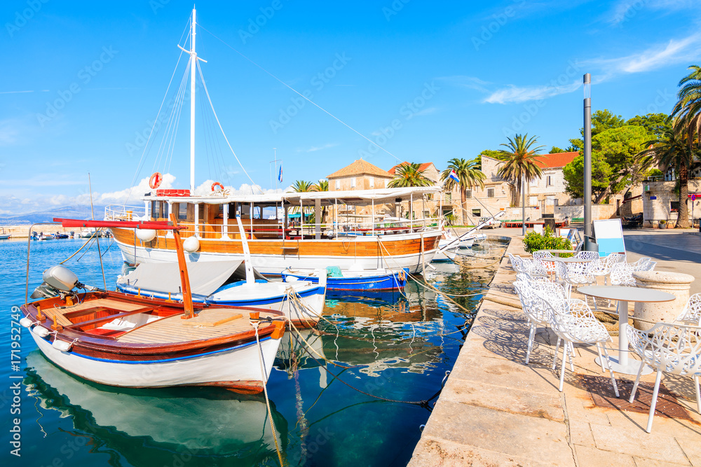 Fishing boats and chairs of local cafe bar in Sutivan port, Brac island, Croatia
