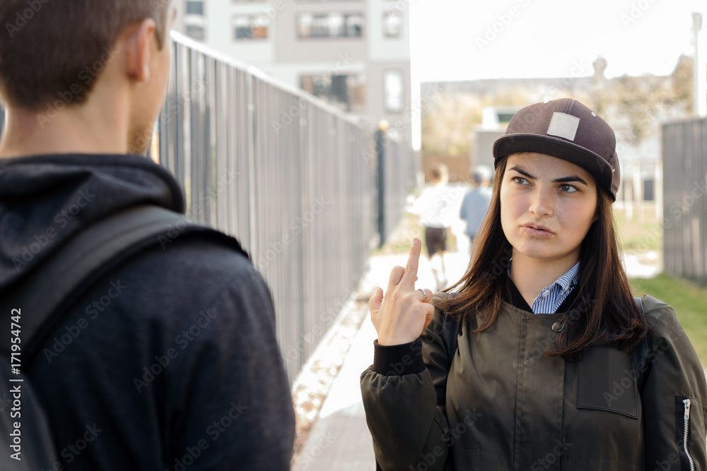 a young girl in the cap shows the middle finger (fuck you sign) with my  boyfriend( man's back) Stock Photo | Adobe Stock