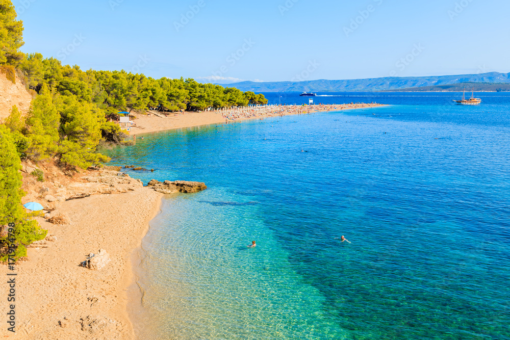 Couple of people swimming on famous Zlatni Rat beach with beautiful sea water in Bol town, Brac island, Croatia