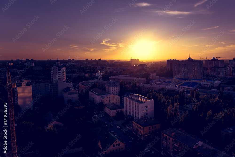 Purple sunset over the city, dramatic lighting of the cityscape, view from the roof