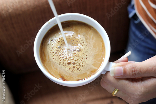 pouring creamer into a cup of coffee photo