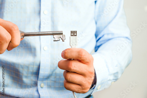 Man holds a key in his hand and tries to open USB. Cyber security and data security on the memory card against hacking. Isolated, white background.