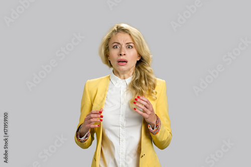 Portrait frightened shocked scared woman. Younf woman wearing formal wear looking stunned and terrified on grey background.
