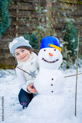 Portrait of a little girl and snowman outdoor. Christmas concept.