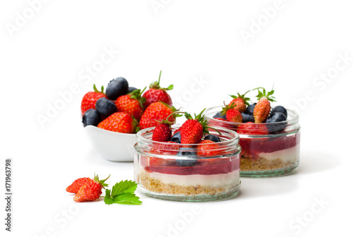 Mini  wild forest berries cheesecake in a glass pots isolated on white background