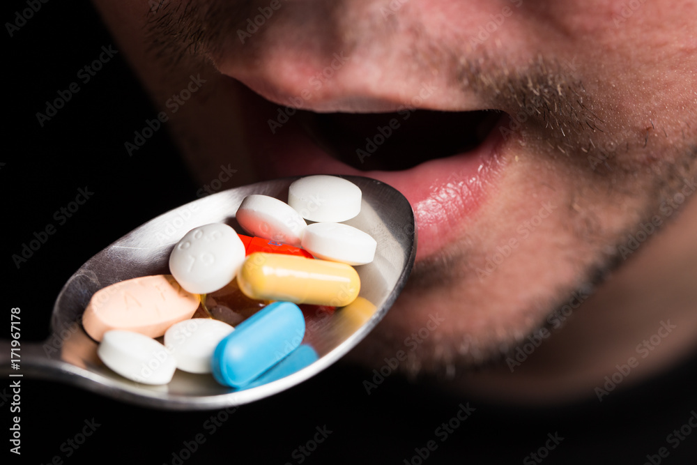 Fotografie Man eating pills with a spoon