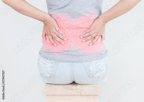 Portrait of young woman touching her back with pained expression, suffering from backache after long working hours, Healthy concept.