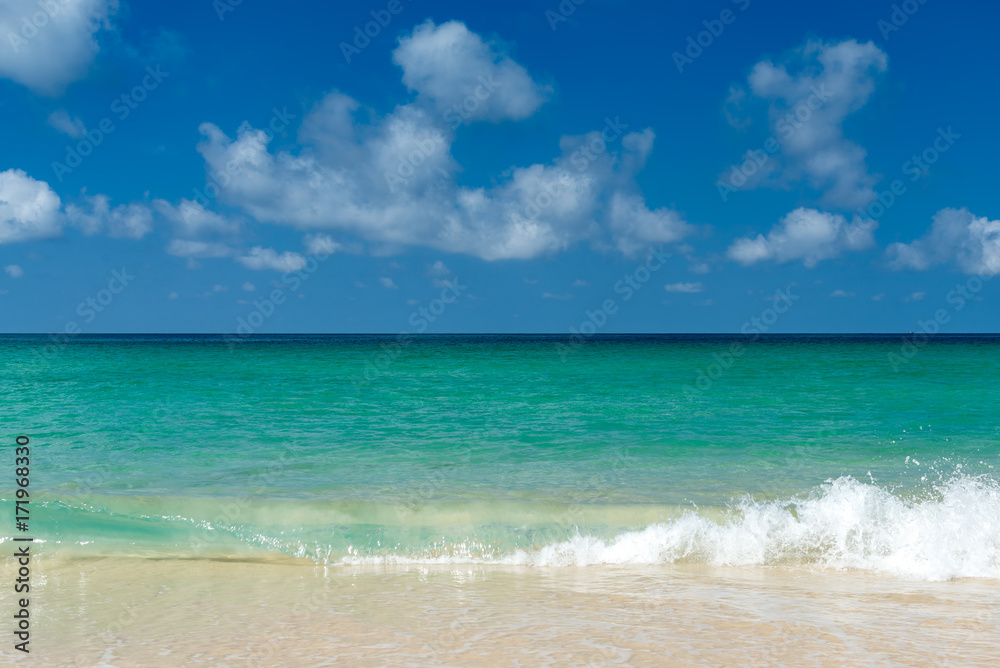 blue sea and white wave on beach with blue sky and clouds on sunny day
