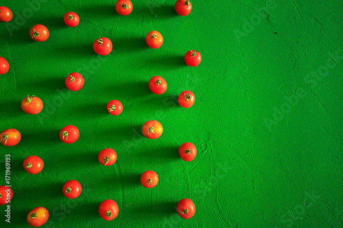 Red tomatoes cherry, scattered in a chaotic manner on a green background. Food background.