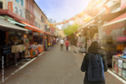 Backpack asian girl has traveling and shopping at China Town outdoor market with sunrise in the morning at Singapore.