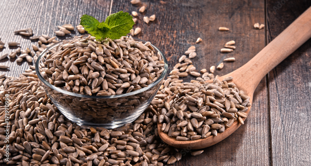 Composition with bowl of shelled sunflower seeds on wooden table Composition with bowl of shelled sunflower seeds on wooden table