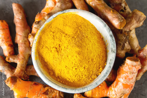 Turmeric powder and fresh turmeric. Dark background. Space for text.
