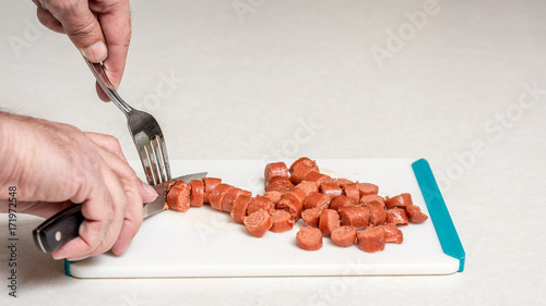 Slicing hotdogs with a knife and fork