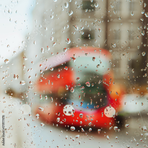 фотография Raindrop on glass and red London bus lights background.