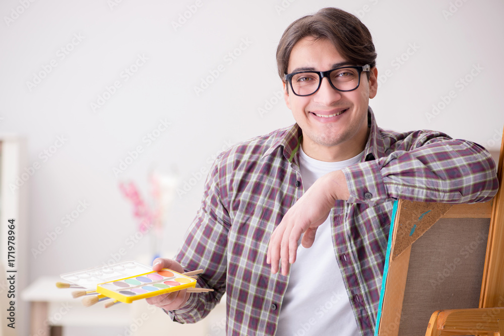 Young male artist drawing pictures in bright studio Young male artist drawing pictures in bright studio