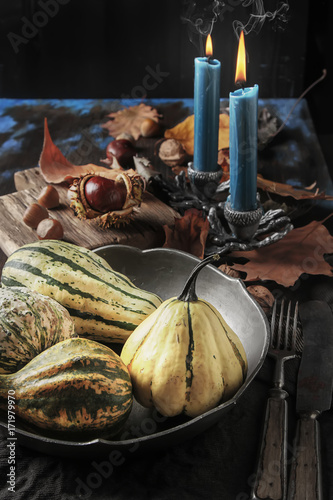 Decorating for Halloween. Small most pumpkin with chestnuts and nuts on a dark wooden background..free space text. Long blue candles