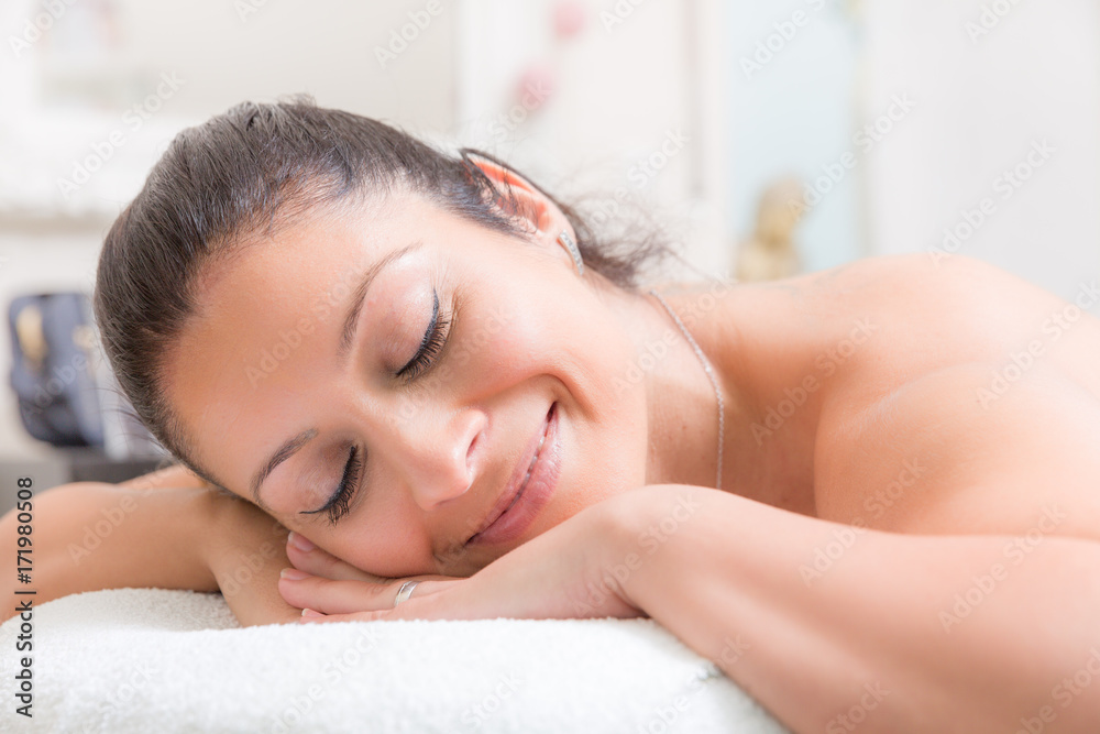 Junge Frau liegt auf einem Massagetiesch und lächelt entspannt Junge Frau liegt auf einem Massagetiesch und lächelt entspannt