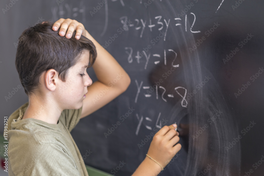 Schoolboy solving a problem on a blackboard. Schoolboy solving a problem on a blackboard.