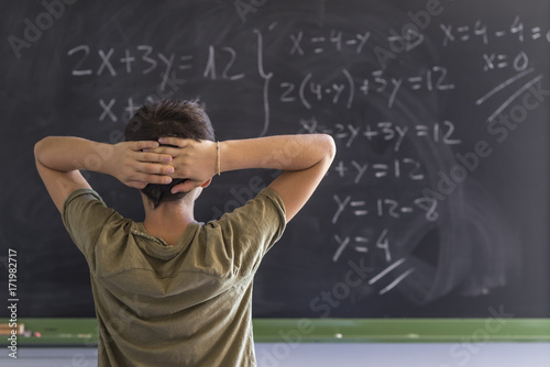 Schoolboy solving a problem on a blackboard.