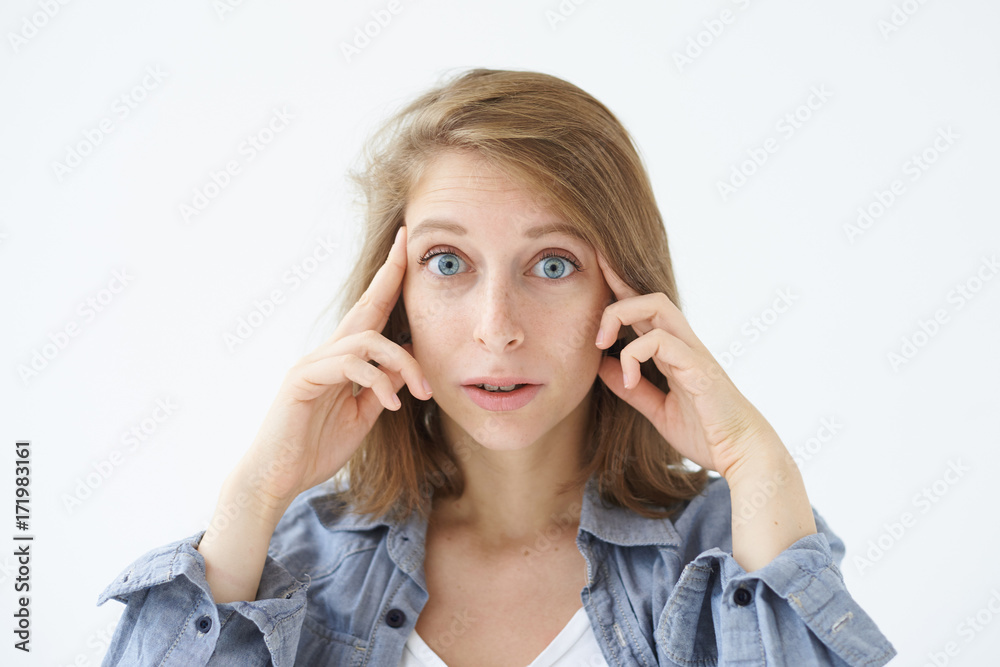 Thoughts, concentration and focus. Serious blue-eyed woman in casual clothes holding fingers on her temples having thoughtful expression. Concentrated female trying to remember or recollect something Thoughts, concentration and focus. Serious blue-eyed woman in casual clothes holding fingers on her temples having thoughtful expression. Concentrated female trying to remember or recollect something