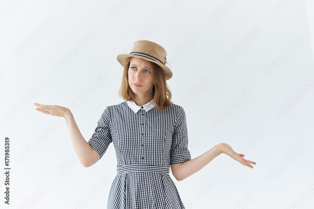 Genuine human emotions, reaction and feelings. Studio picture of indecisive doubtful young lady shrugging shoulders and gesturing in indifference, saying: Who knows, Whatever, It doesn't matter Genuine human emotions, reaction and feelings. Studio picture of indecisive doubtful young lady shrugging shoulders and gesturing in indifference, saying: Who knows, Whatever, It doesn't matter
