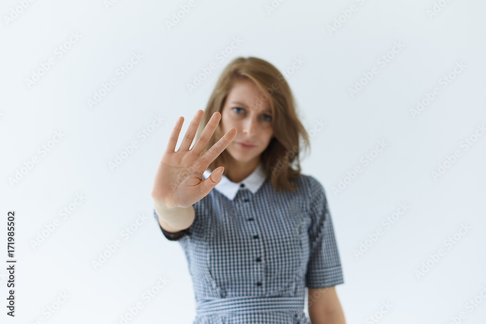 Body language. Refusal, ban, prohibition, denial and rejection. Frustrated young European female in dress stretching out hand, warning someone, showing stop sign. Selective focus on woman's palm Body language. Refusal, ban, prohibition, denial and rejection. Frustrated young European female in dress stretching out hand, warning someone, showing stop sign. Selective focus on woman's palm