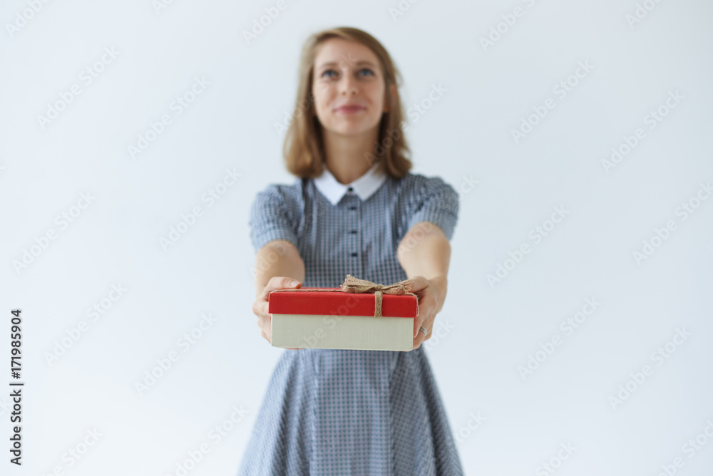 Elegant young Europen lady in collar dress holding big box of present, giving it to her friend on birthday. Attractive girl making gift, posing at studio wall. Selective focus on female's hands Elegant young Europen lady in collar dress holding big box of present, giving it to her friend on birthday. Attractive girl making gift, posing at studio wall. Selective focus on female's hands
