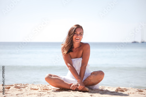 Girl sitting in dress on beach
