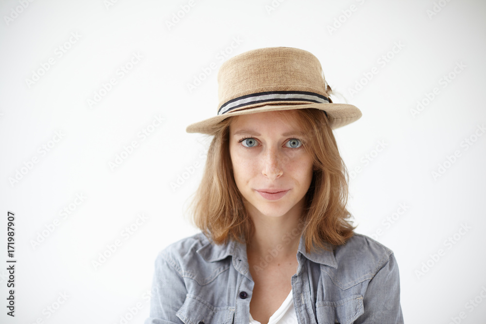 Cropped shot of sad Caucasian girl with pure freckled skin and big beautiful blue eyes standing isolated in studio wearing round retro hat and casual clothes, staring at camera with serious expression Cropped shot of sad Caucasian girl with pure freckled skin and big beautiful blue eyes standing isolated in studio wearing round retro hat and casual clothes, staring at camera with serious expression