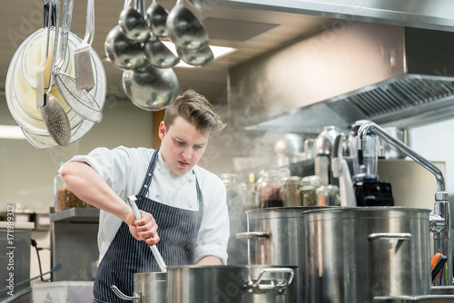 Portrait of a dedicated young head chef cooking in the commercial kitchen of a hotel photo