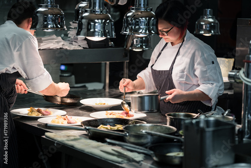 Dedicated young woman styling savory dish while working as a cook in an exclusive restaurant