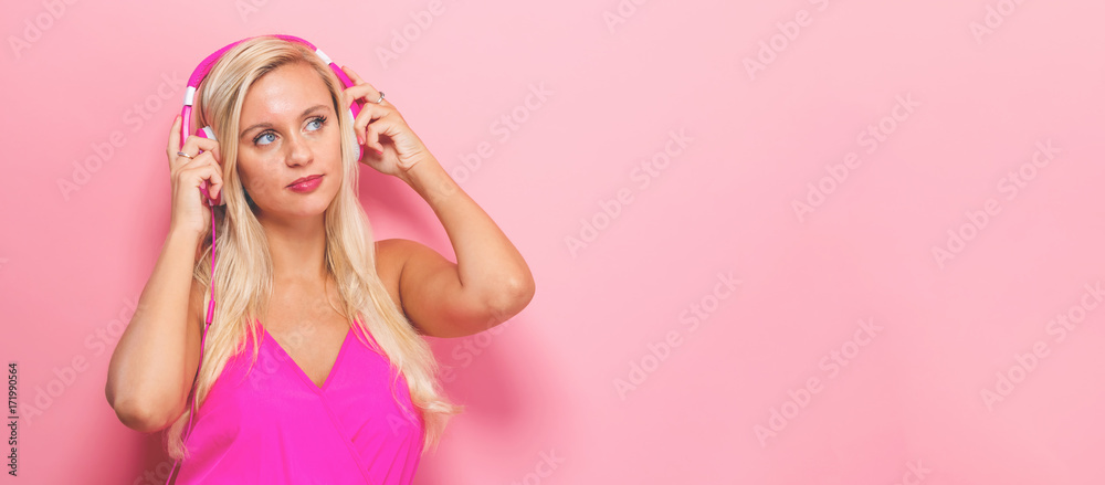 Happy young woman with headphones on a pink background Happy young woman with headphones on a pink background