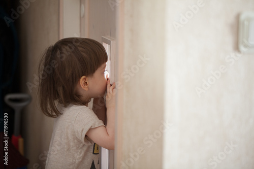 Fotografie The little boy looks in the window of the door