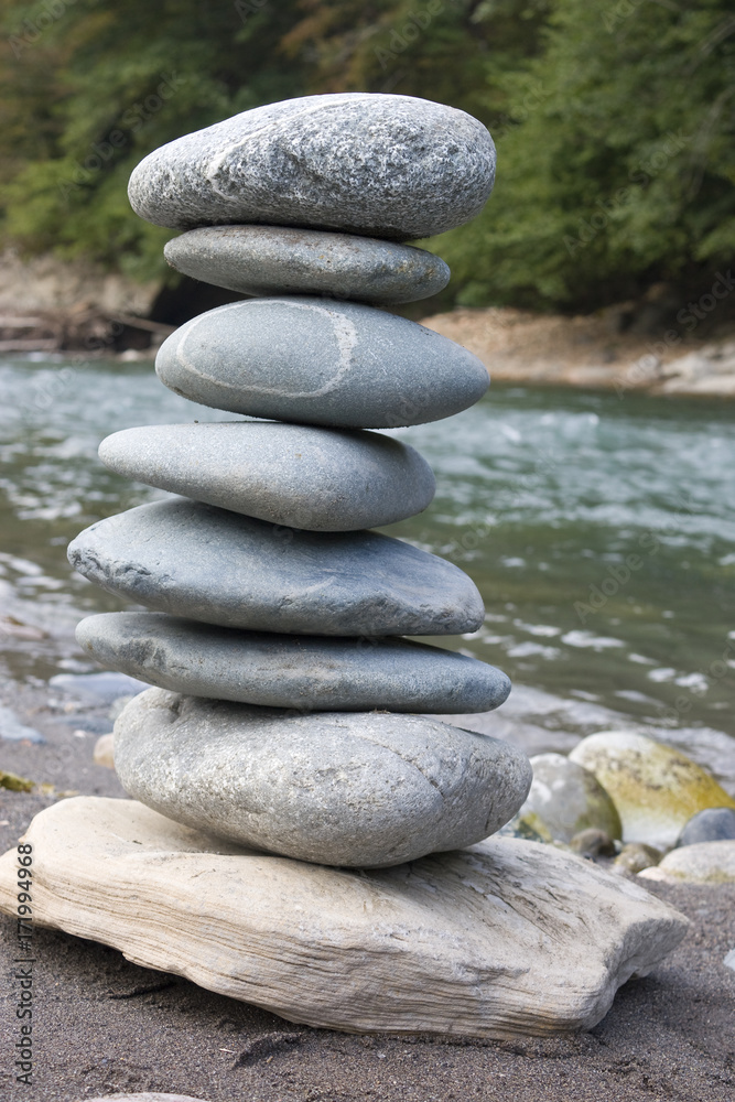 Pyramid of stones on the banks of the river. Stones pyramid on sand symbolizing zen, harmony, balance. Pyramid of stones on the banks of the river. Stones pyramid on sand symbolizing zen, harmony, balance.