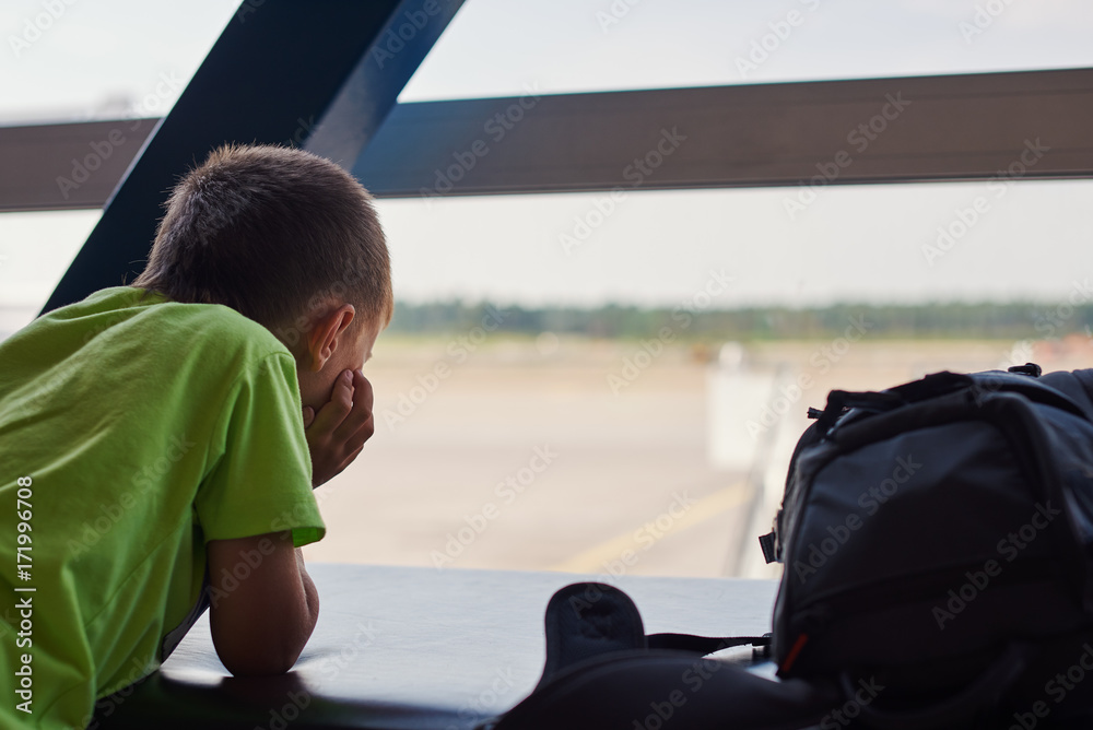 Сute Caucasian boy waiting for boarding time in the airport.