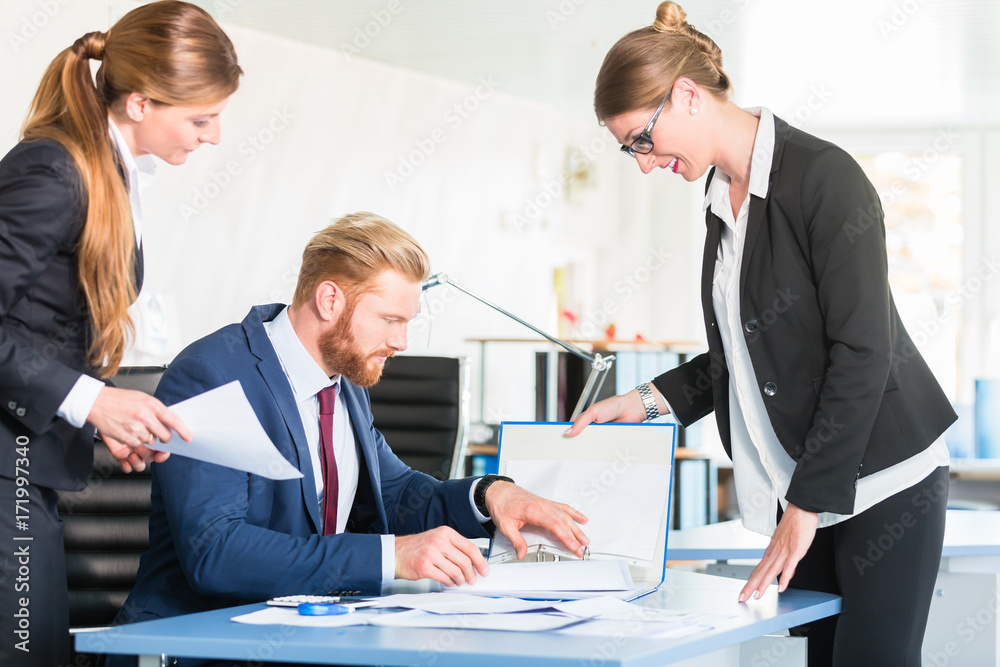 Manager is checking documents brought by two assistants Manager is checking documents brought by two assistants