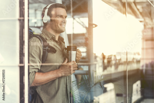 Positive traveler male is enjoying his favorite song