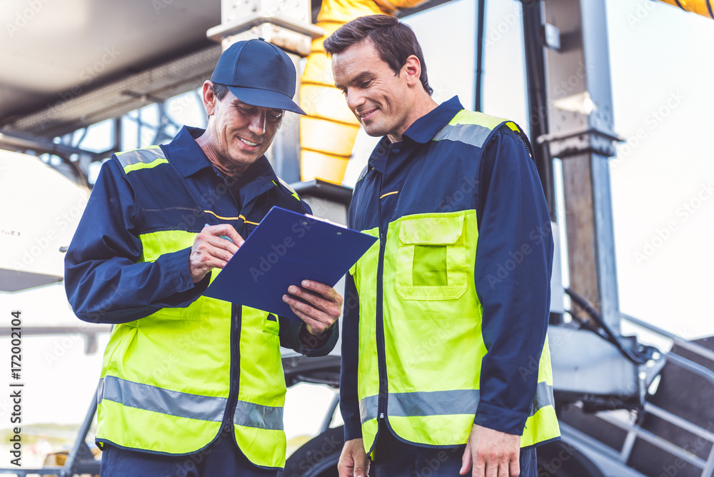 Outgoing man noting document near happy comrade Outgoing man noting document near happy comrade