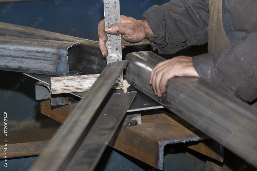 Metalworking shop workers work behind machines and apparatuses to create steel structures. Metalworking shop workers work behind machines and apparatuses to create steel structures.